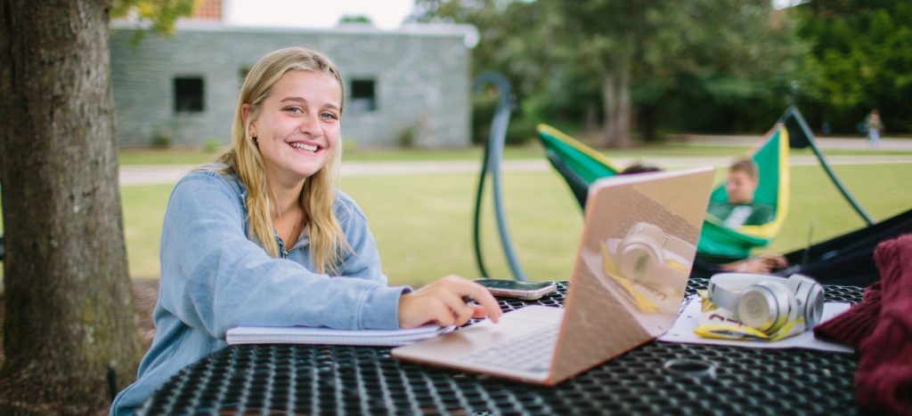 Student working on laptop on the quad